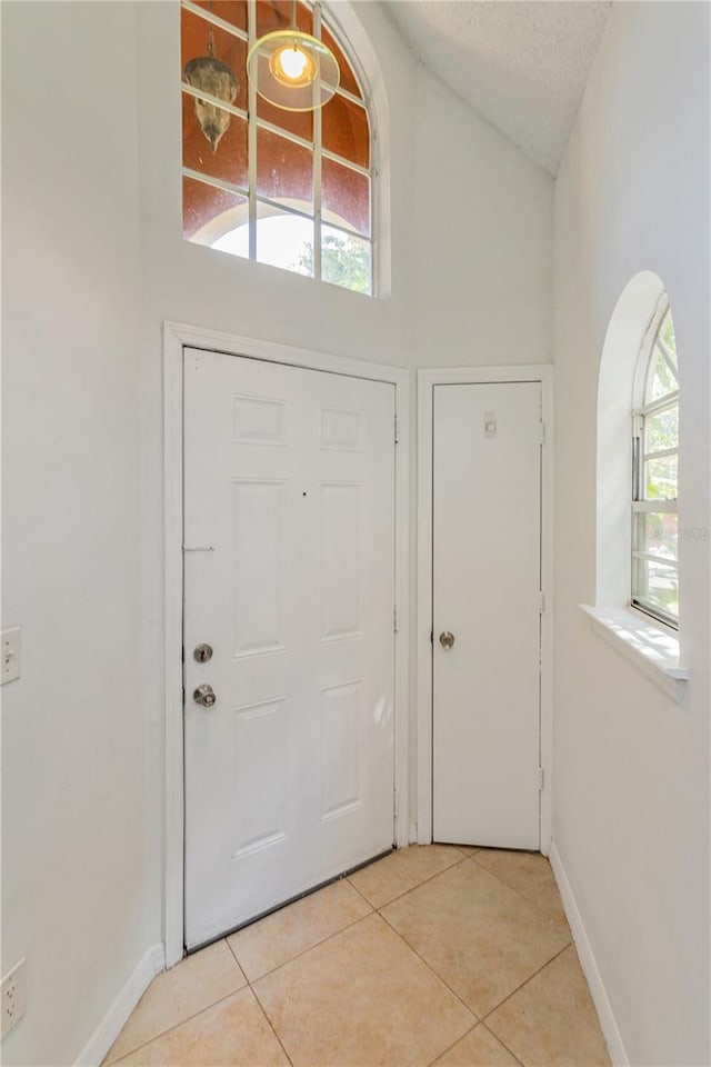 entrance foyer with light tile patterned floors, a textured ceiling, and a wealth of natural light