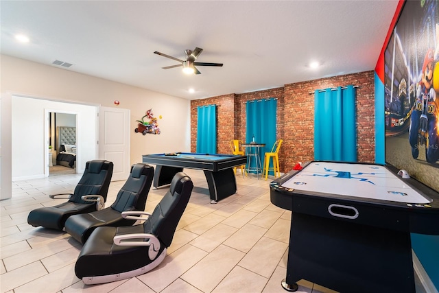 game room with ceiling fan, brick wall, and light tile patterned floors