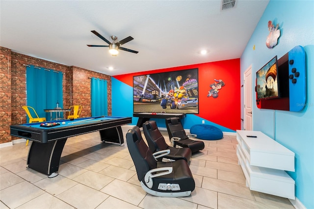 rec room featuring brick wall, light tile patterned floors, and ceiling fan