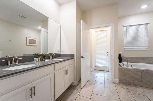 bathroom featuring vanity, tile patterned floors, and tiled tub