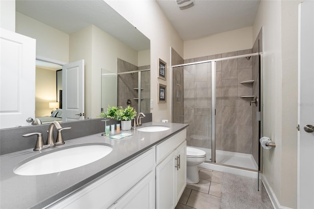 bathroom featuring toilet, tile patterned flooring, vanity, and a shower with door