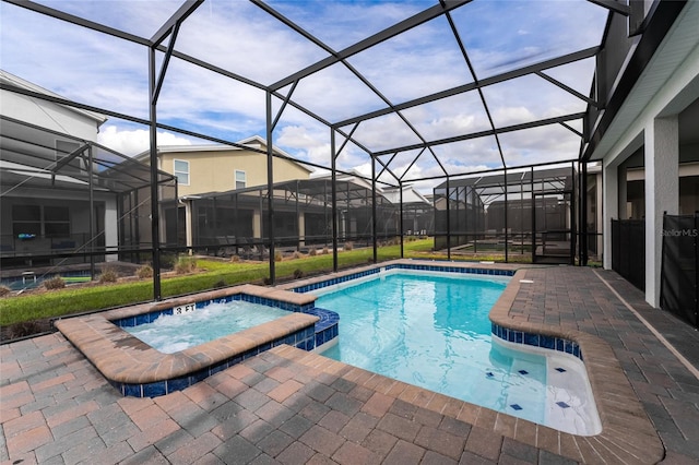 view of pool featuring a patio, an in ground hot tub, and glass enclosure