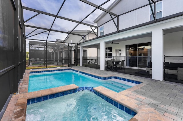 view of pool featuring an in ground hot tub, a patio, glass enclosure, and ceiling fan