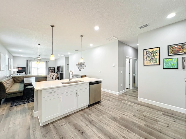 kitchen featuring dishwasher, a center island with sink, sink, decorative light fixtures, and white cabinetry