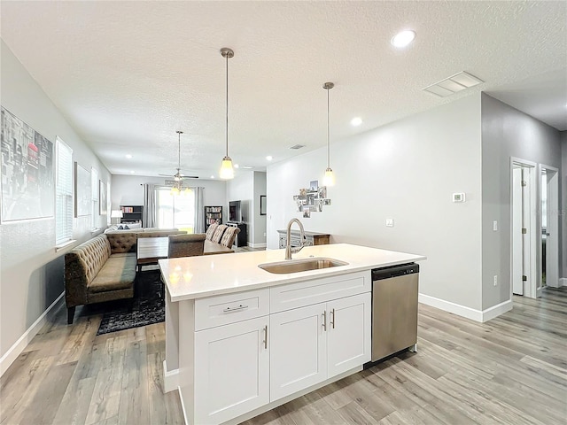 kitchen with pendant lighting, a kitchen island with sink, sink, stainless steel dishwasher, and white cabinetry