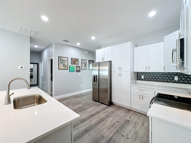 kitchen with light stone counters, white cabinetry, sink, and appliances with stainless steel finishes