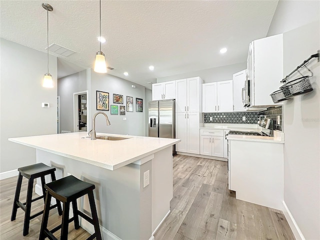 kitchen with white cabinets, sink, hanging light fixtures, and appliances with stainless steel finishes