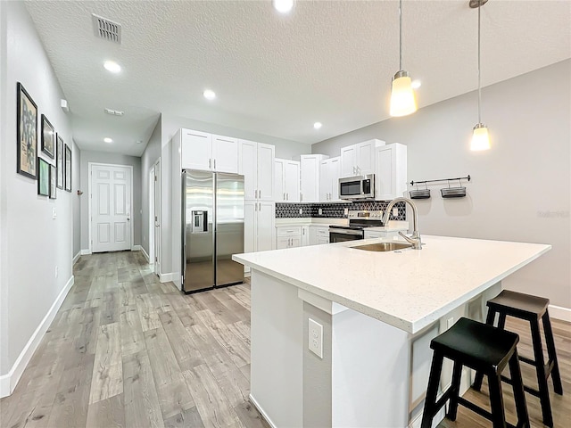 kitchen featuring sink, decorative backsplash, decorative light fixtures, white cabinetry, and stainless steel appliances