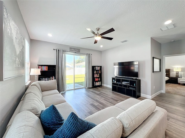 living room featuring ceiling fan, a healthy amount of sunlight, a textured ceiling, and light wood-type flooring