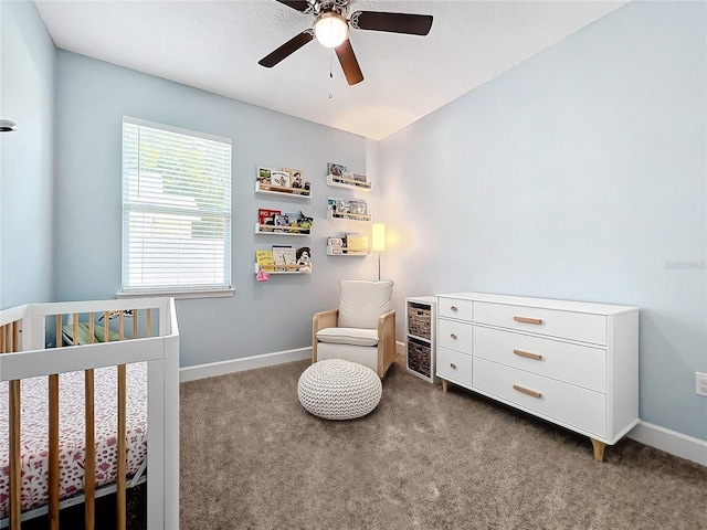 bedroom featuring dark colored carpet, ceiling fan, and a crib