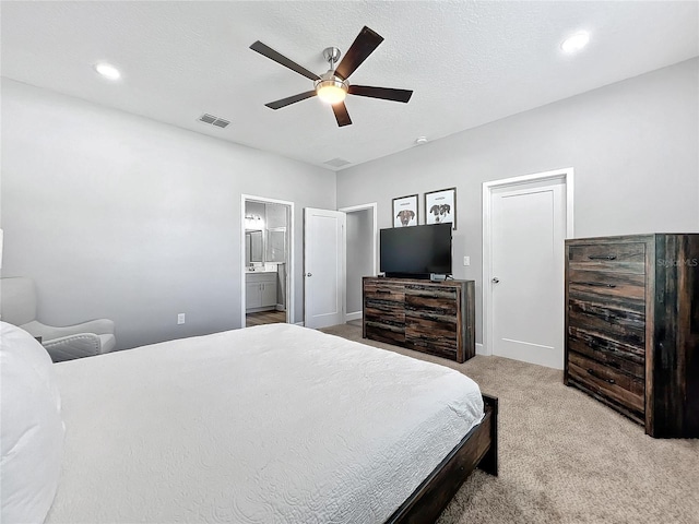 carpeted bedroom featuring ceiling fan, ensuite bathroom, and a textured ceiling