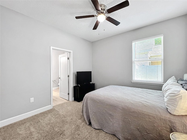 carpeted bedroom featuring a textured ceiling, ensuite bath, and ceiling fan