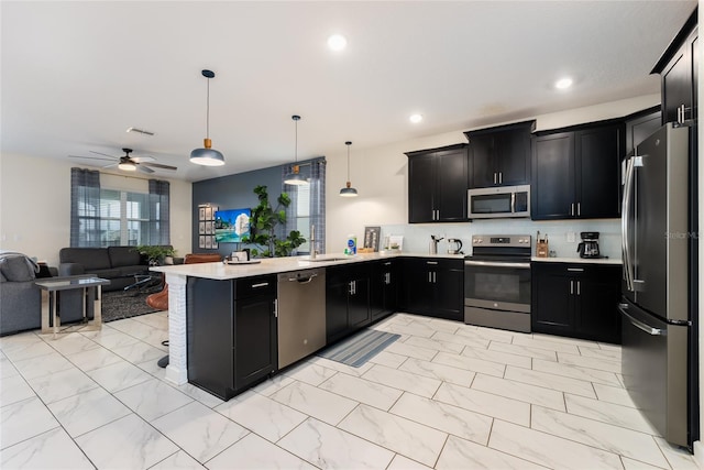 kitchen featuring hanging light fixtures, appliances with stainless steel finishes, kitchen peninsula, and ceiling fan