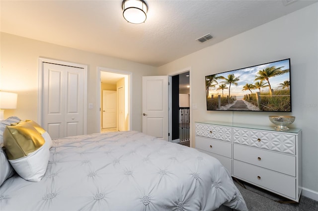 bedroom featuring a closet, a textured ceiling, and dark colored carpet