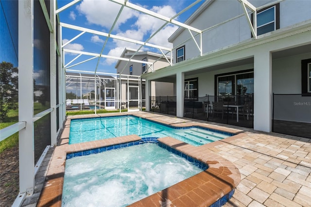 view of pool featuring a patio area, an in ground hot tub, and glass enclosure