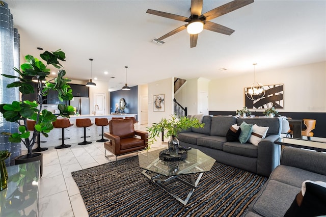 living room with sink and ceiling fan with notable chandelier