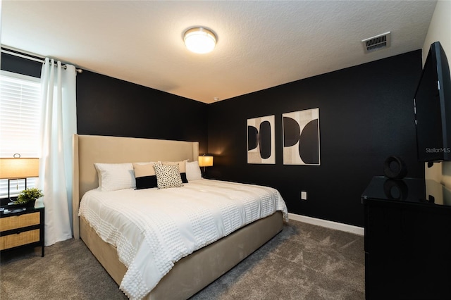 bedroom featuring dark carpet and a textured ceiling