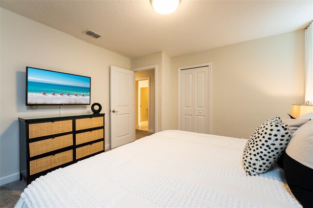 carpeted bedroom with a closet and a textured ceiling