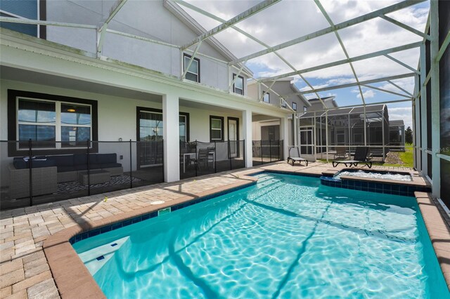 view of swimming pool with an in ground hot tub, a patio area, and glass enclosure