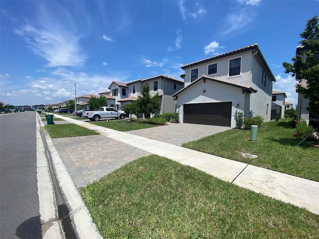 view of front of home with a front yard, driveway, stucco siding, a garage, and a residential view