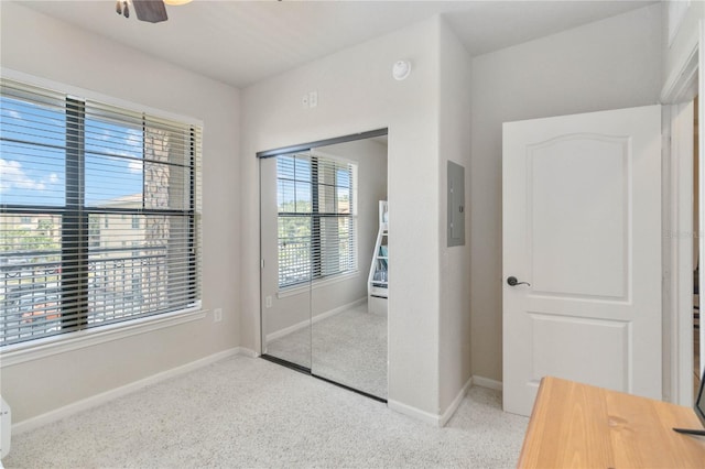 unfurnished bedroom with a closet, electric panel, light colored carpet, and ceiling fan