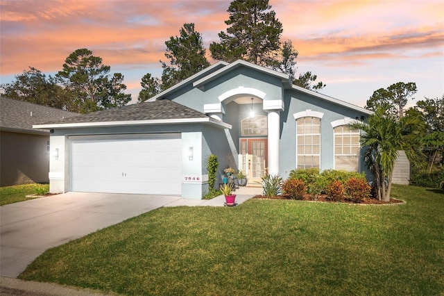 ranch-style house with stucco siding, a lawn, driveway, an attached garage, and french doors