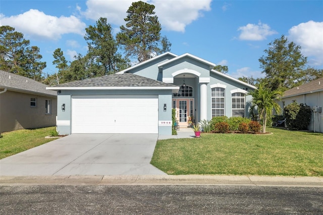 ranch-style house with a garage, stucco siding, a front yard, and driveway
