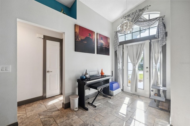 entrance foyer with a towering ceiling, stone finish flooring, a notable chandelier, and baseboards