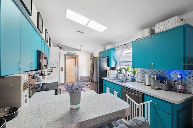 kitchen with backsplash, blue cabinets, vaulted ceiling, and stainless steel appliances
