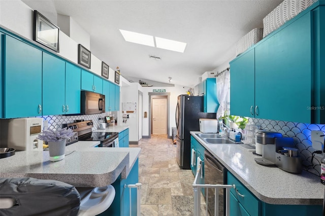 kitchen with stainless steel appliances, stone tile flooring, backsplash, a sink, and lofted ceiling with skylight