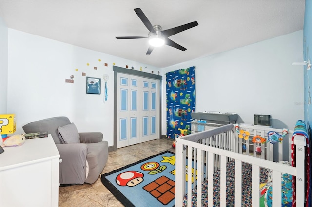 bedroom featuring a nursery area and ceiling fan