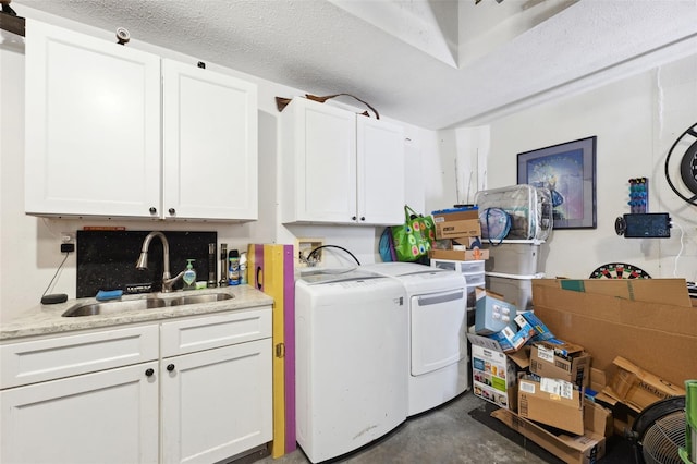 clothes washing area featuring cabinets, a textured ceiling, sink, and washing machine and clothes dryer