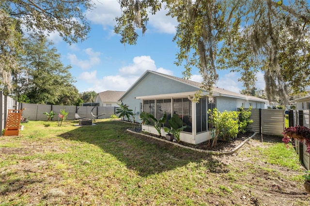 view of yard featuring a sunroom, a fire pit, and a fenced backyard