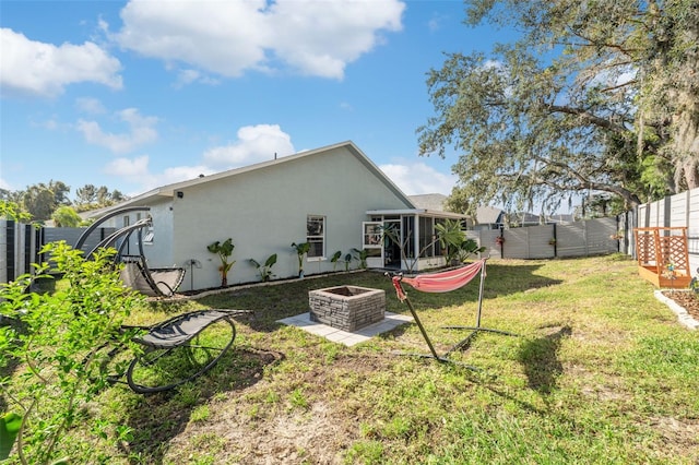 back of property featuring a lawn, a fire pit, and a sunroom