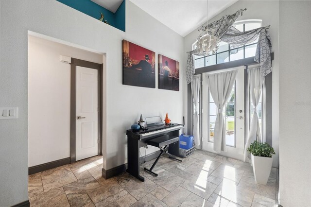 entrance foyer with a towering ceiling, stone finish floor, a chandelier, and baseboards