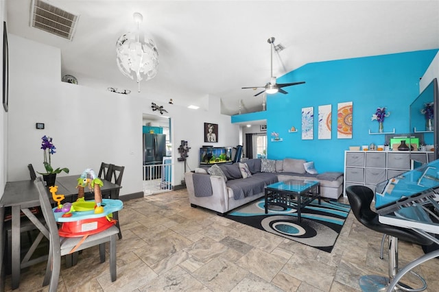 living area featuring stone finish flooring, visible vents, baseboards, a ceiling fan, and high vaulted ceiling