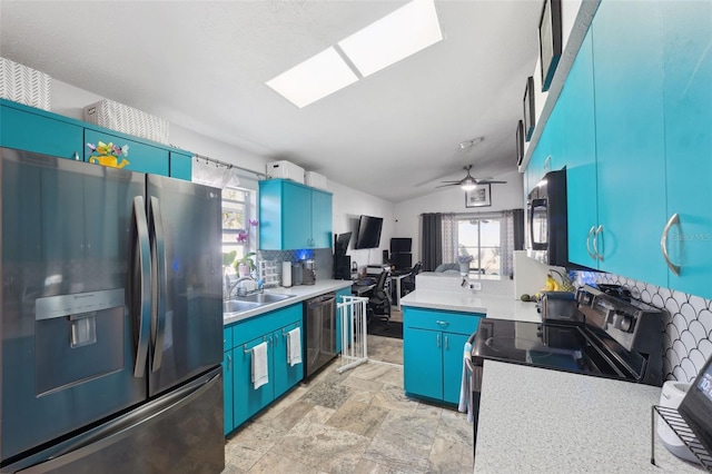 kitchen with tasteful backsplash, a sink, appliances with stainless steel finishes, vaulted ceiling with skylight, and blue cabinets