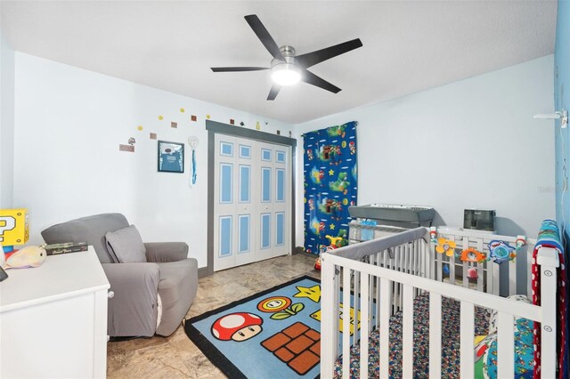 bedroom featuring a nursery area, a ceiling fan, and a closet
