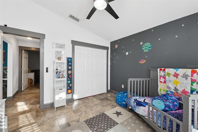 bedroom with a closet, stone finish flooring, baseboards, visible vents, and lofted ceiling