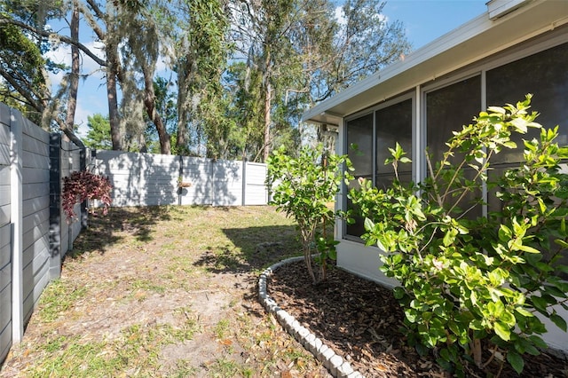 view of yard featuring a sunroom and a fenced backyard
