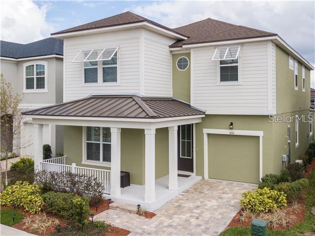 1861 Sawyer Palm Pl, Kissimmee, FL 34747 - view of front facade featuring covered porch, a standing seam roof, an attached garage, driveway, and metal roof