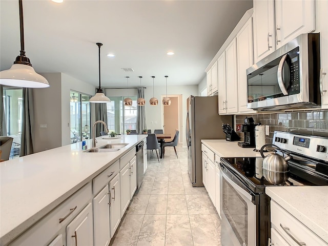 kitchen featuring decorative light fixtures, white cabinets, stainless steel appliances, and sink