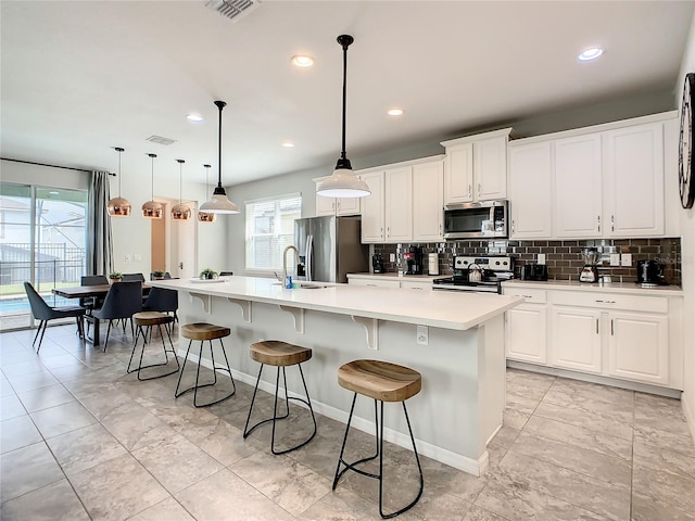 kitchen featuring a wealth of natural light, appliances with stainless steel finishes, decorative light fixtures, and white cabinets