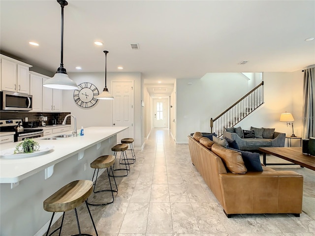 kitchen featuring a kitchen island with sink, sink, pendant lighting, appliances with stainless steel finishes, and tasteful backsplash