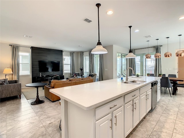 kitchen with dishwasher, a kitchen island with sink, sink, decorative light fixtures, and white cabinets