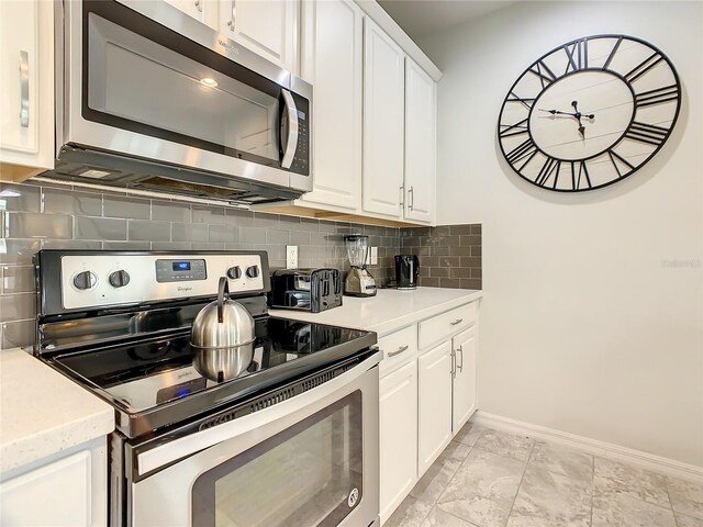 1861 Sawyer Palm Pl, Kissimmee, FL 34747 - kitchen with appliances with stainless steel finishes, baseboards, light countertops, tasteful backsplash, and white cabinetry