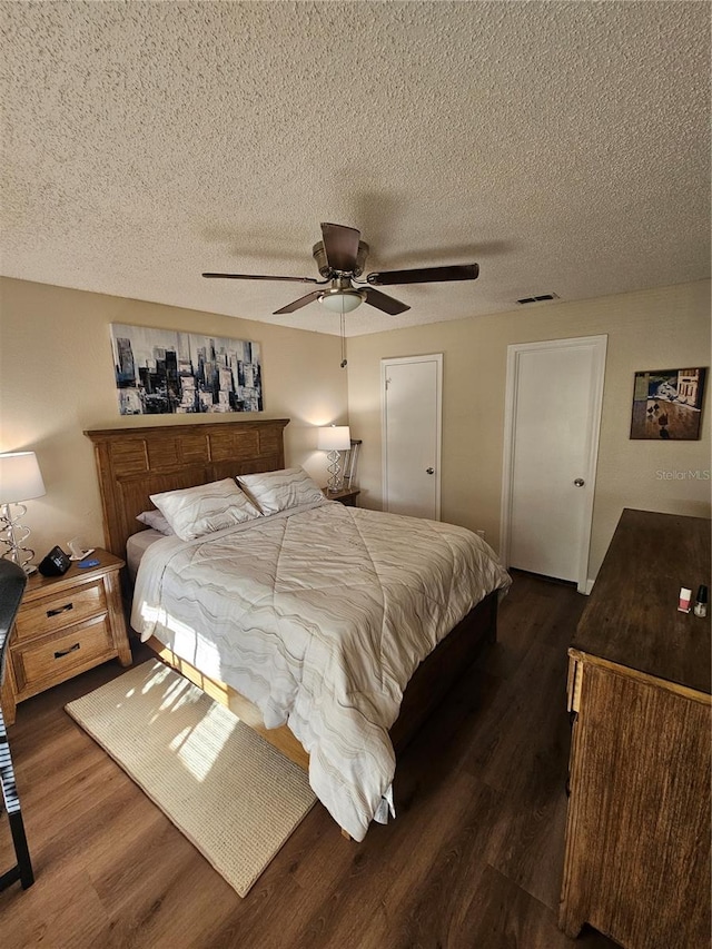 bedroom with ceiling fan, a textured ceiling, and dark hardwood / wood-style flooring