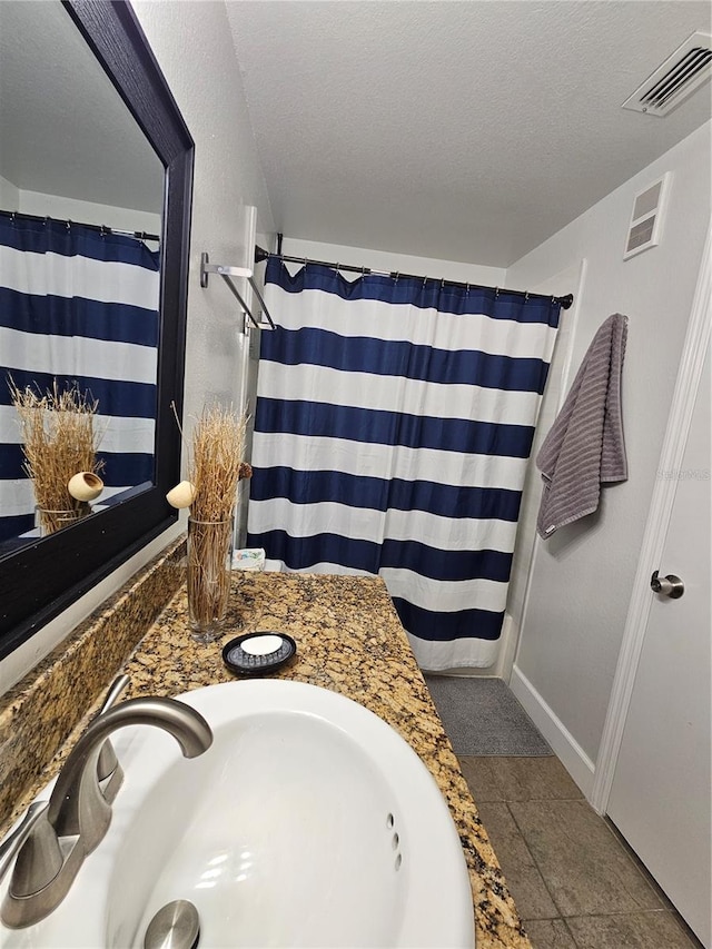 bathroom featuring vanity, a textured ceiling, and tile patterned floors