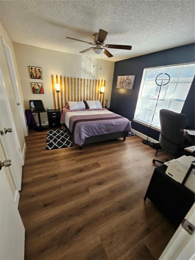 bedroom with ceiling fan, a textured ceiling, and dark hardwood / wood-style flooring