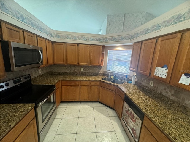 kitchen featuring high vaulted ceiling, dark stone countertops, light tile patterned flooring, sink, and stainless steel appliances